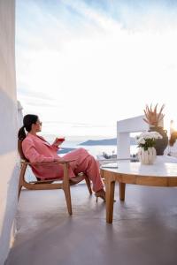 a woman sitting in a chair looking at her cell phone at CASA SUNSHA SANTORINI in Fira