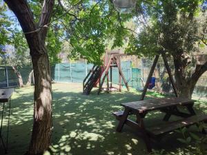 un parque infantil con un columpio de madera y un árbol en ELIANNA HOUSE, en Paralio Astros