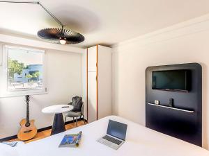 um quarto com uma secretária com um computador portátil e uma televisão em Hotel ibis Evora em Évora