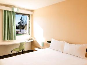 ein Schlafzimmer mit einem Bett, einem Fenster und einem Stuhl in der Unterkunft Hotel ibis Evora in Évora