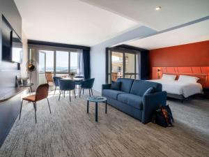 フレジュスにあるMercure Thalasso & Spa Port Fréjusの青いソファとベッドが備わるホテルルームです。