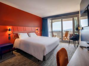 フレジュスにあるMercure Thalasso & Spa Port Fréjusの大きなベッドとバルコニーが備わるホテルルームです。
