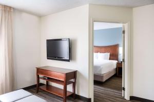 a hotel room with a bed and a flat screen tv at Hyatt House Herndon/Reston in Herndon