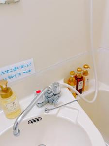 a bathroom sink with a faucet and bottles of oil at ひまわりHotel in Nagasaki