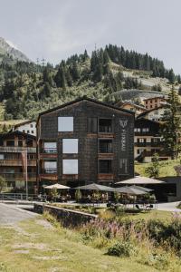 ein Gebäude mit Tischen und Sonnenschirmen davor in der Unterkunft Fuxbau in Stuben am Arlberg
