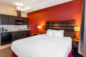 a hotel room with a large bed and a kitchen at Best Western Plus Kindersley Hotel in Kindersley
