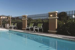 a swimming pool with chairs and a fence at La Quinta by Wyndham Fairfield - Napa Valley in Fairfield