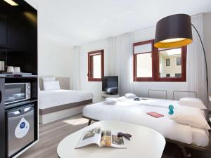 Habitación de hotel con 2 camas y mesa en Novotel Suites Perpignan Centre en Perpiñán