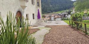 un patio de un edificio con una sombrilla púrpura en Ansitz Heufler en Rasun di Sopra