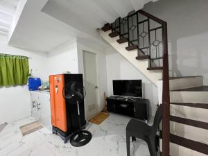 a living room with a staircase with a television and a chair at Affordable 2 storey transient house with free wifi in Camella Homes Koronadal in Carpenter