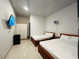 a bedroom with two beds and a flat screen tv at Bình Minh Homestay - Dốc Lết in Doc Let