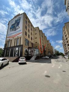 un gran edificio con coches estacionados frente a él en Апартаменты Tropicana, en Samarkand