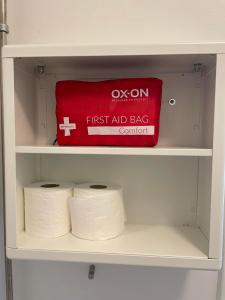 un estante con una bolsa de primeros auxilios y dos rollos de papel higiénico en KragenæsHus, en Torrig