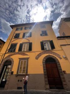 een vrouw die voor een geel gebouw staat bij La casa del papavero in Lucca