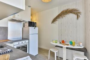 eine Küche mit einem weißen Kühlschrank und einem Tisch in der Unterkunft LE SPOT -T2 à 100m de la grande plage in Saint-Gilles-Croix-de-Vie
