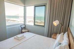 a bedroom with a bed with a view of the ocean at Bokkombaai in Bloubergstrand