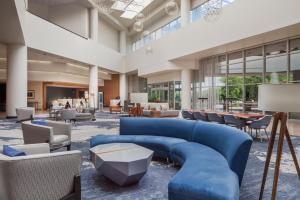 um grande átrio com um sofá azul e cadeiras em Sheraton Arlington Hotel em Arlington