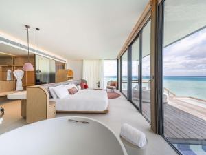 SO/ Maldives في مالي أتول الجنوبية: غرفة نوم مع سرير وشرفه مع المحيط