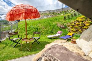 a patio with chairs and an umbrella on the grass at HEART - Manufaktur Appartements in Sölden