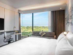 巴吞他尼的住宿－诺富特曼谷兰实未来公园酒店，卧室配有一张白色的大床和一张沙发。