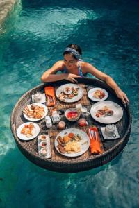 Una donna seduta a un tavolo con del cibo in acqua di Le Indochina Hotel & Beach Da Nang City a Da Nang