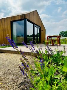 a small wooden building with a table and purple flowers at Waterlinie Lodges in Utrecht
