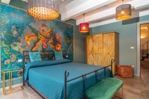 ein Schlafzimmer mit einem blauen Bett und einer farbenfrohen Wand in der Unterkunft Sikelia Relais 2 in Linguaglossa