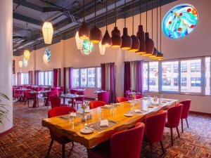 ナイロビにあるMövenpick Hotel & Residences Nairobiの長テーブルと赤い椅子が備わるレストラン