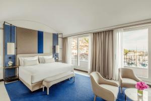 システィアーナにあるTivoli Portopiccolo Sistiana Wellness Resort & Spaのベッド1台と椅子2脚が備わるホテルルームです。