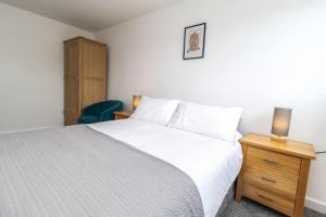 ein Schlafzimmer mit einem weißen Bett und einem hölzernen Nachttisch in der Unterkunft Free Driveway Parking 3 Double Bedroom House, Ideal for long term contractor, etc stays, 4 miles 11 mins drive to Nissan, 20 mins drive to Sunderland Newcastle, Fast WIFI - see Dwellcome Home Ltd site for assurance in Jarrow + 15 Fotos
