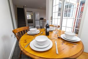 einen Holztisch mit weißen Gerichten und einer Flasche Wein in der Unterkunft Free Driveway Parking 3 Double Bedroom House, Ideal for long term contractor, etc stays, 4 miles 11 mins drive to Nissan, 20 mins drive to Sunderland Newcastle, Fast WIFI - see Dwellcome Home Ltd site for assurance in Jarrow