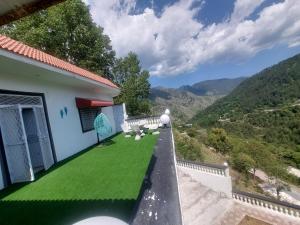 - un balcon avec de l'herbe verte sur le côté d'une maison dans l'établissement Nature Hill Lodge (Mountain Holiday House), à Abbottabad