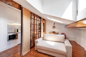 uma sala de estar com um sofá branco e uma cozinha em The Almada Flats no Porto