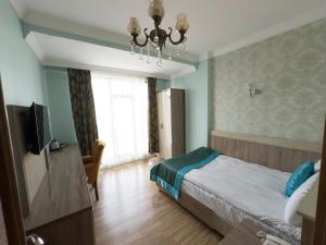 ein Schlafzimmer mit Bett, Fernseher und Kronleuchter in der Unterkunft Kars Center Hotel in Kars