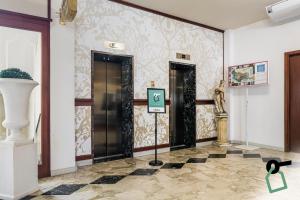 um hall de entrada com duas portas e uma placa num piso de azulejo em HOTIDAY Hotel Cefalù em Cefalù