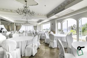 een kamer met witte tafels en stoelen en een kroonluchter bij HOTIDAY Hotel Cefalù in Cefalù