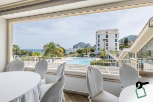 een kamer met een groot raam met witte stoelen en een zwembad bij HOTIDAY Hotel Cefalù in Cefalù