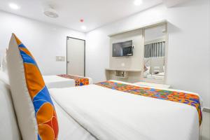 a white room with two beds and a tv at FabHotel Grey Sky in Gandhinagar