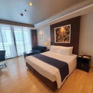 a hotel room with a large bed and a living room at Admiral Premier Bangkok in Bangkok