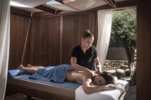 Elounda Infinity Exclusive Resort & Spa - Adults Only في إيلوندا: امرأة تقوم بعمل مساج على السرير