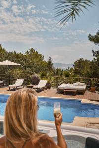 Villa B&M Experience في Sant Francesc de s'Estany: امرأة جالسة في حوض الاستحمام عقد كوب من النبيذ