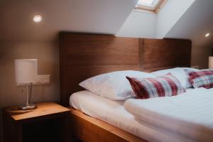 Schlafzimmer mit einem Bett mit einem Kopfteil aus Holz und Kissen in der Unterkunft Das Eisenberg in Sankt Martin an der Raab