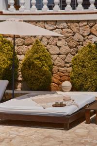Villa B&M Experience في Sant Francesc de s'Estany: مرتبة الجلوس امام جدار حجري