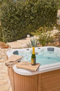 Villa B&M Experience في Sant Francesc de s'Estany: حوض استحمام ساخن مع زجاجة من النبيذ وكؤوس من النبيذ