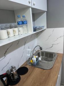 a kitchen counter with a sink and bottles of water at Apart-Hotel Tobayakova 25 in Almaty