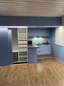 an empty kitchen with blue cabinets and a counter at Apartments Weintrauben in Pärnu