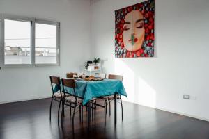 a dining room with a table with chairs and a painting at LE SITE in Specchia