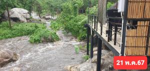 eine Brücke über einen Fluss mit Felsen und Bäumen in der Unterkunft Lunda Orchid Resort in Suan Phung