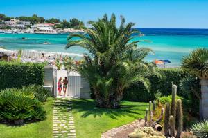 un giardino con una palma e la spiaggia di La Plage a Fontane Bianche