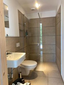La salle de bains est pourvue de toilettes, d'un lavabo et d'une douche. dans l'établissement Teichland Linum Apartments, à Fehrbellin
